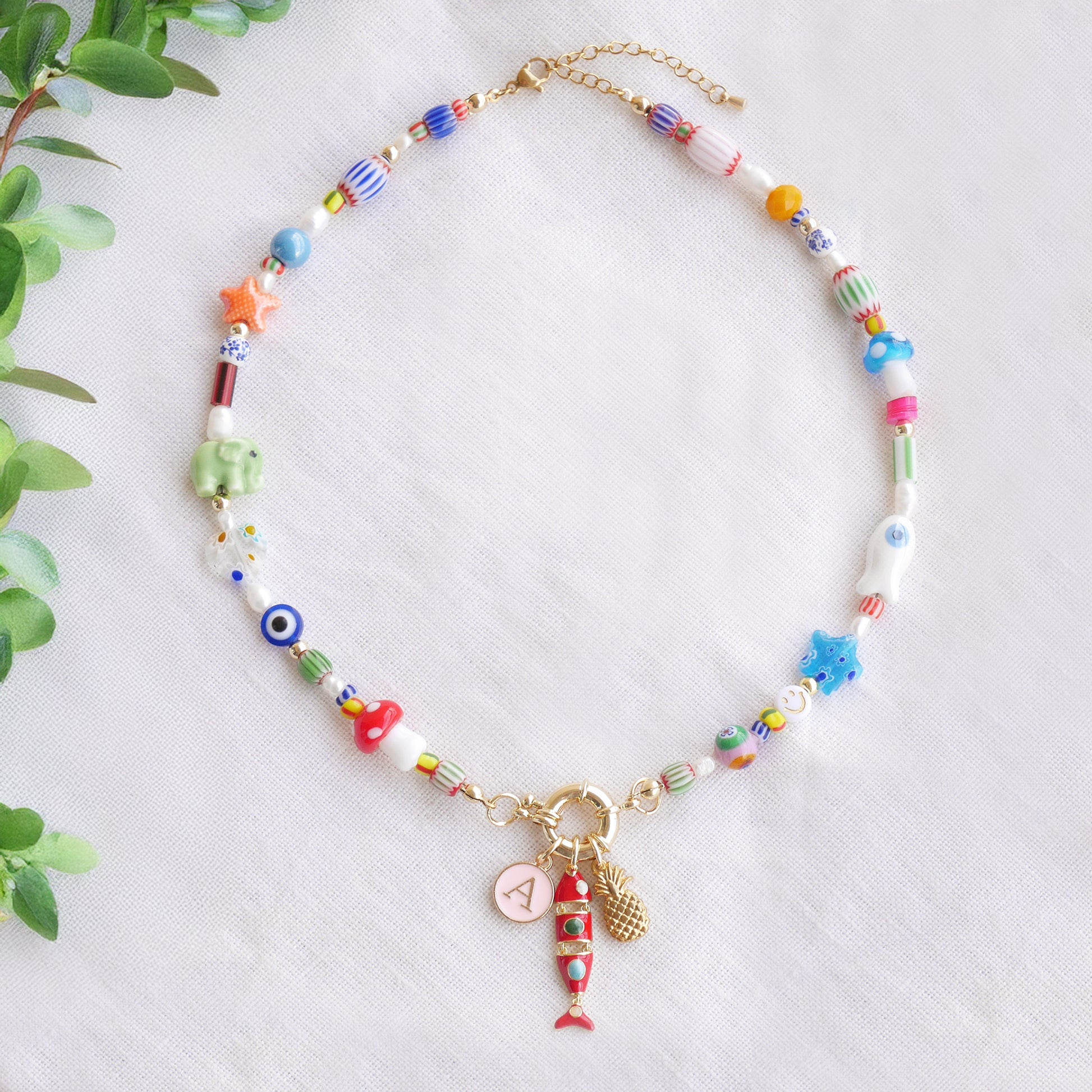 Colorful mixed beads necklace with custom charms, on a white cloth.
