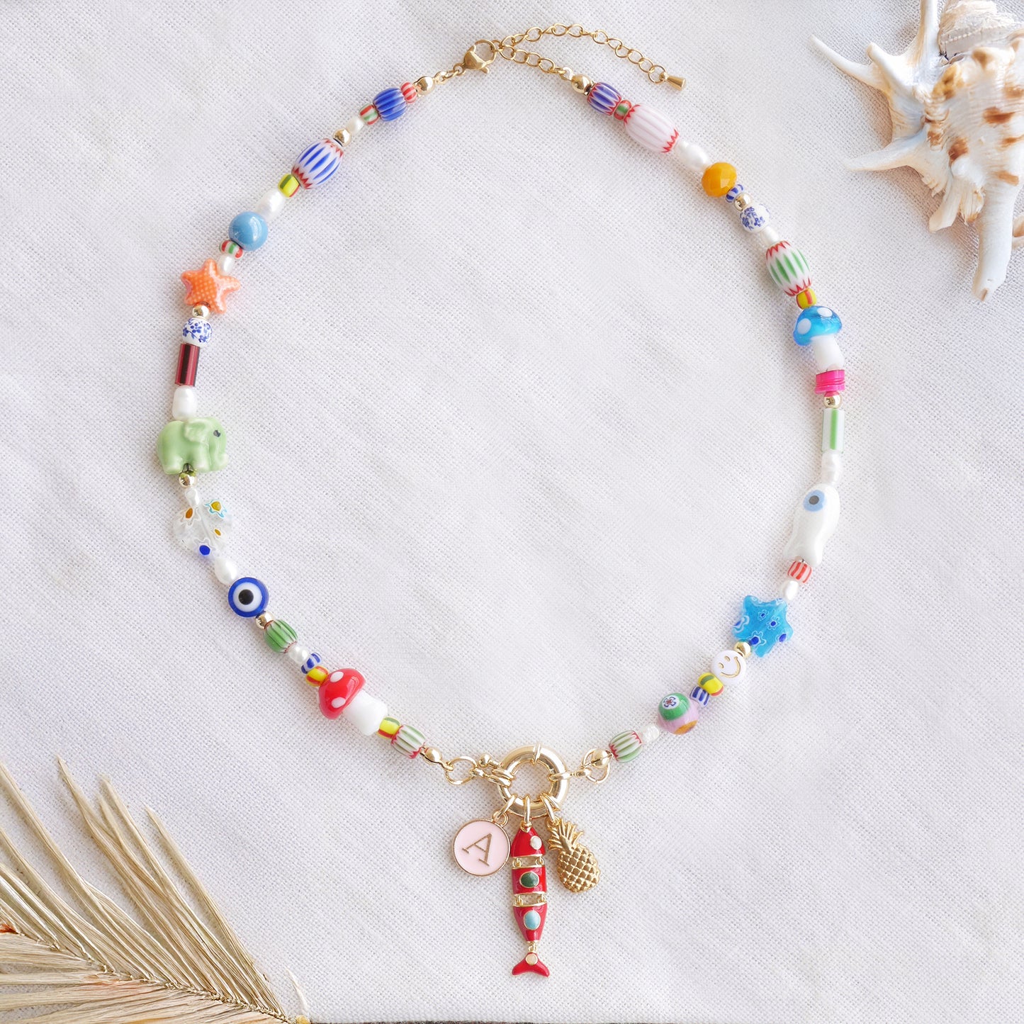 Colorful mixed beads necklace with custom charms, on a white cloth.