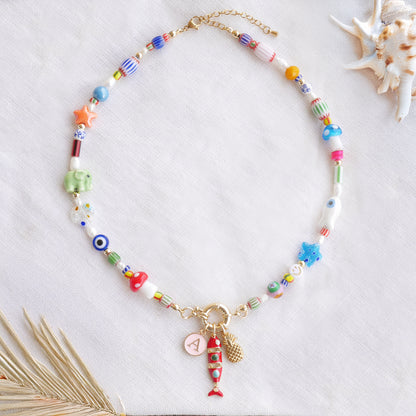 Colorful mixed beads necklace with custom charms, on a white cloth.