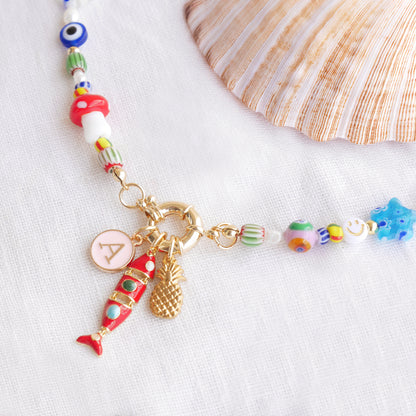 Colorful mixed beads necklace with custom charms, on a white cloth.