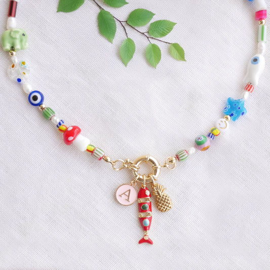 Colorful mixed beads necklace with custom charms, on a white cloth.