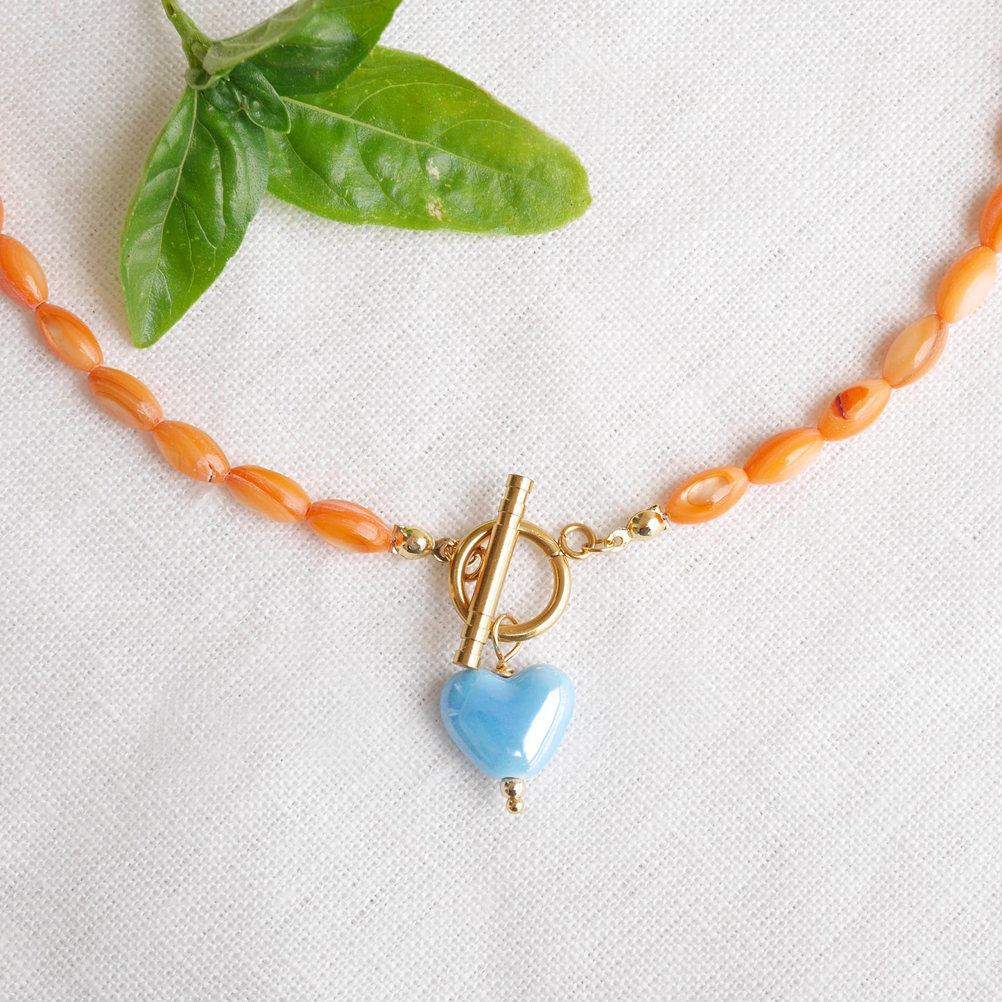 Orange beaded necklace - blue porcelain heart charm, toggle clasp
