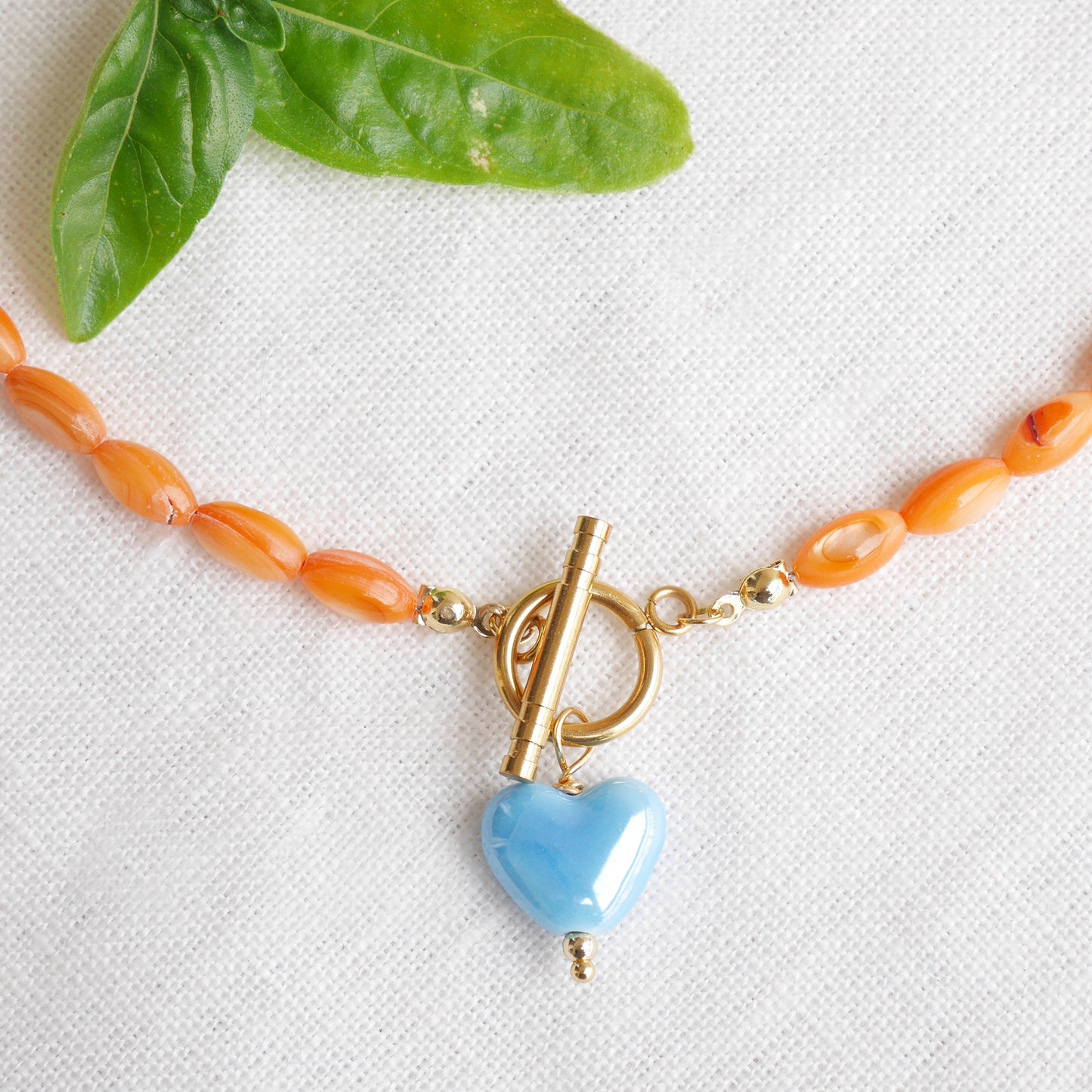 Orange beaded necklace - blue porcelain heart charm, toggle clasp