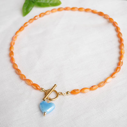 Orange beaded necklace - blue porcelain heart charm, toggle clasp