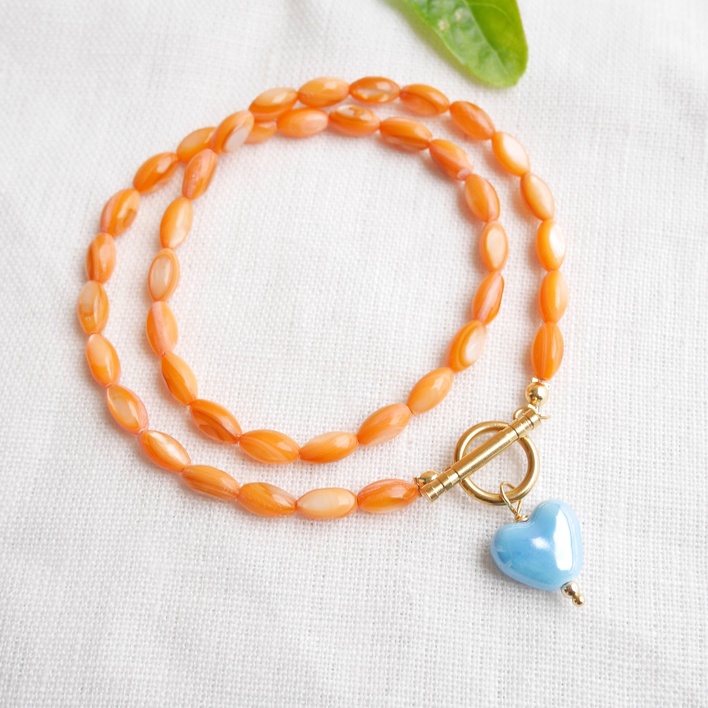 Orange beaded necklace - blue porcelain heart charm, toggle clasp