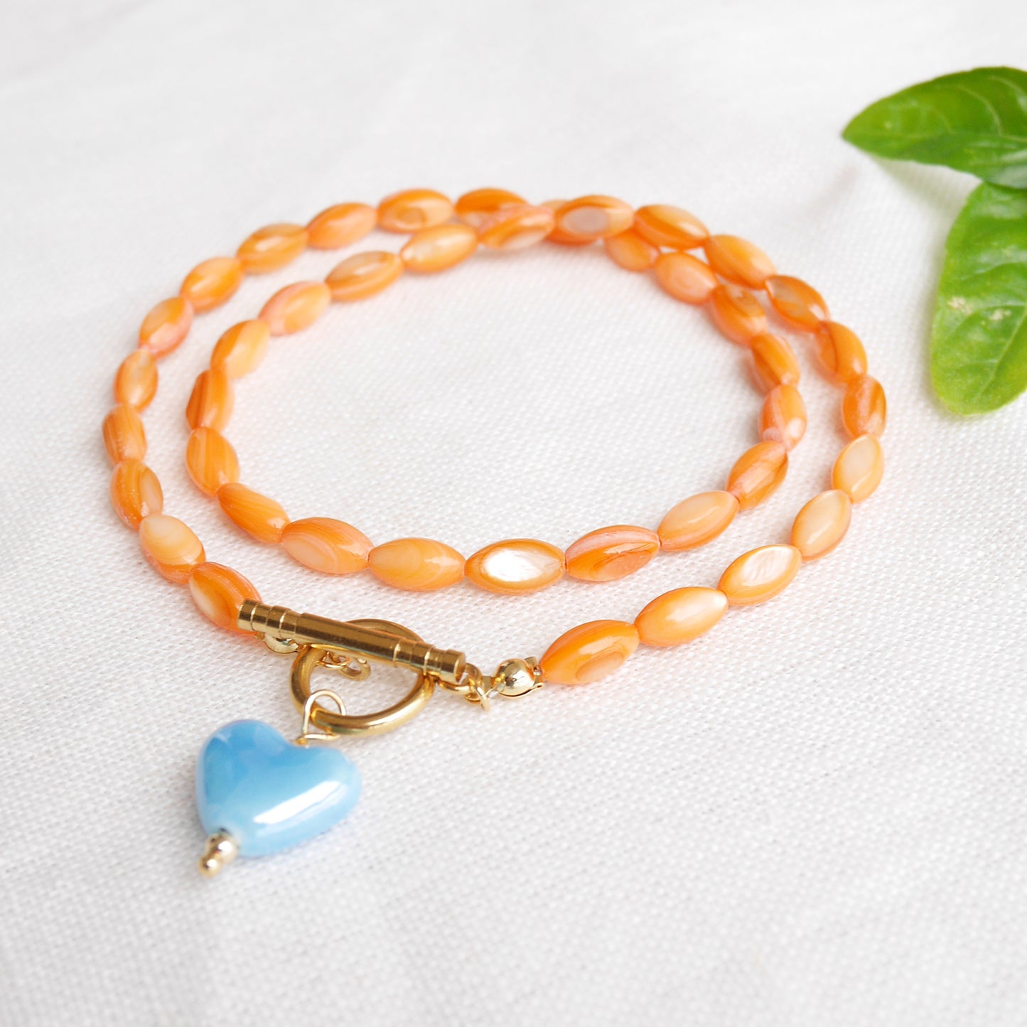 Orange beaded necklace - blue porcelain heart charm, toggle clasp