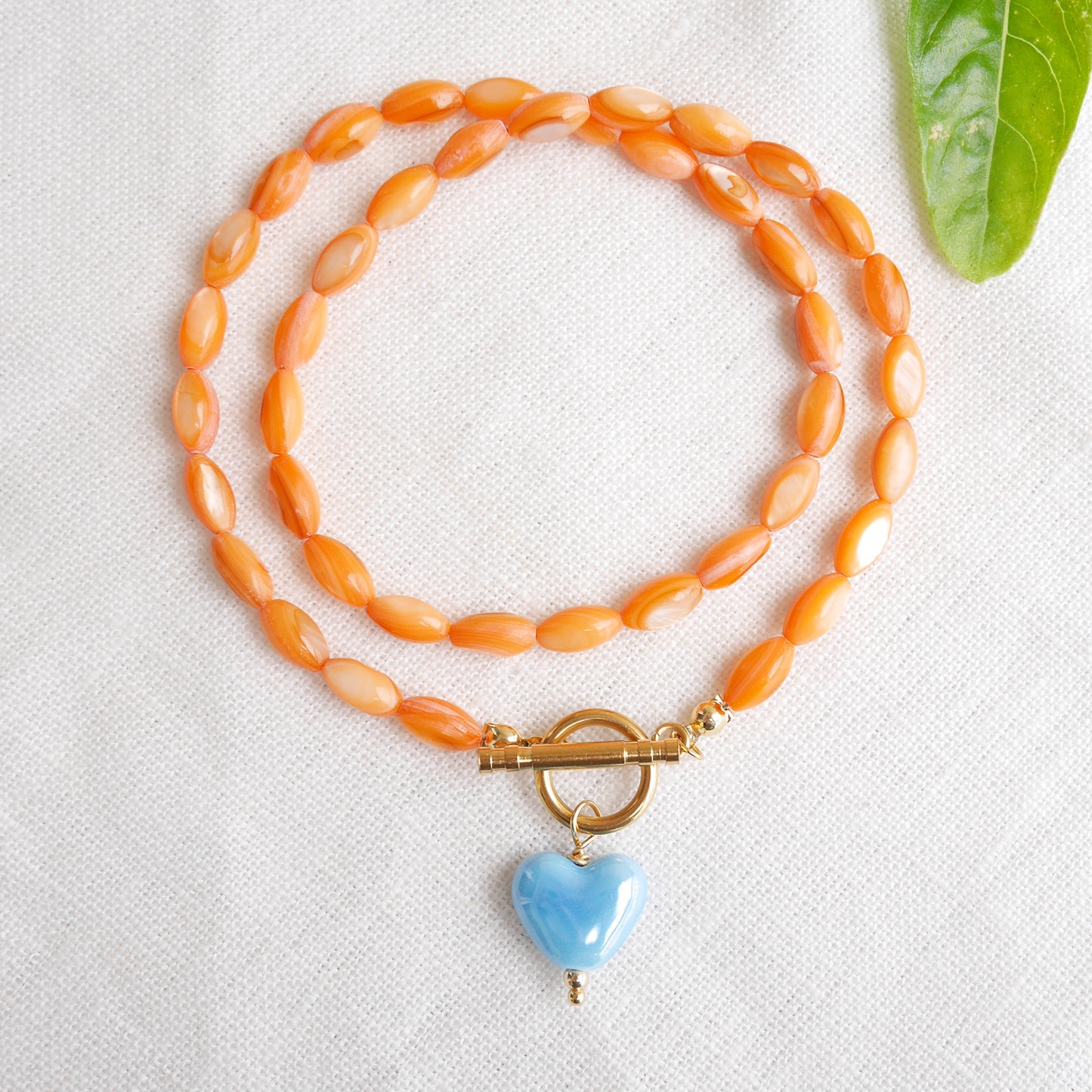 Orange beaded necklace - blue porcelain heart charm, toggle clasp