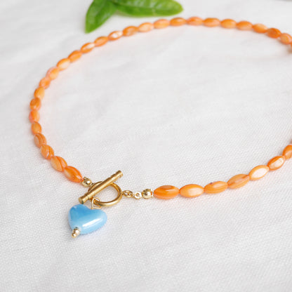 Orange beaded necklace - blue porcelain heart charm, toggle clasp