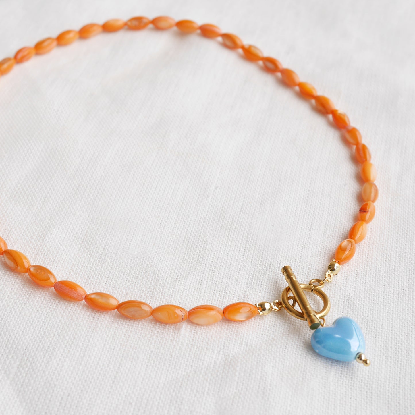 Orange beaded necklace - blue porcelain heart charm, toggle clasp