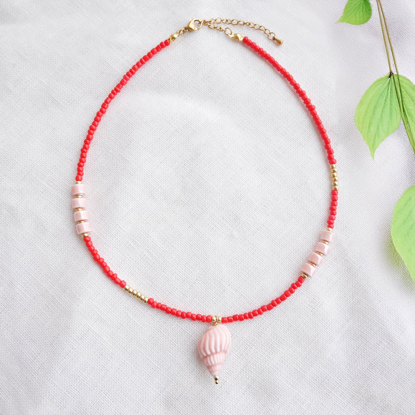 Beaded red conch shell necklace, on a white cloth.