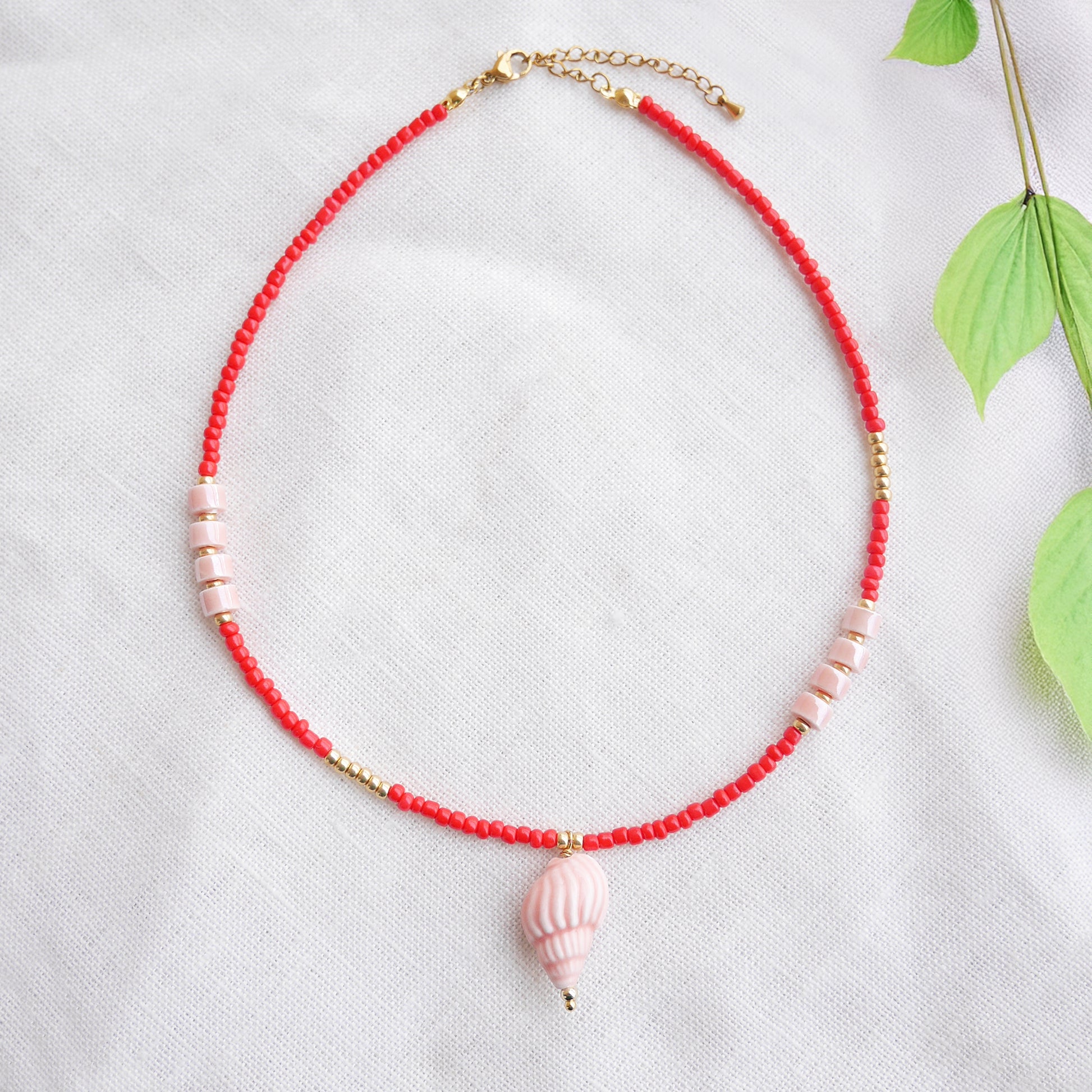 Beaded red conch shell necklace, on a white cloth.