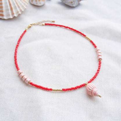 Beaded red conch shell necklace, on a white cloth.