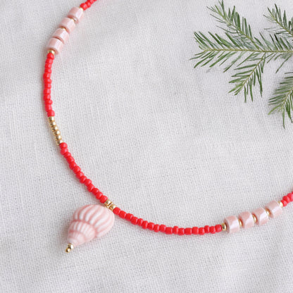 Beaded red conch shell necklace, on a white cloth.