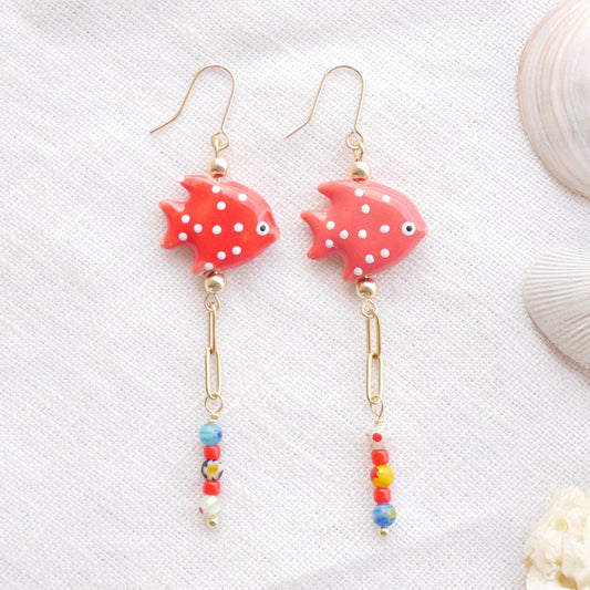 Red fish dangle earrings on a white cloth