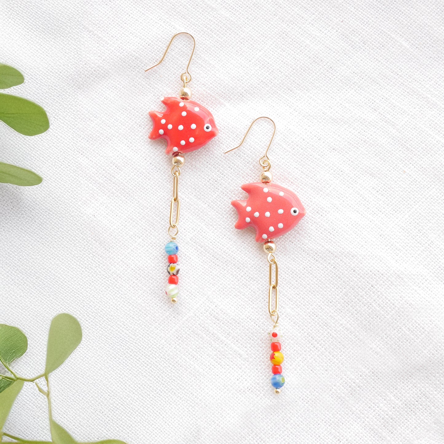 Red fish dangle earrings on a white cloth