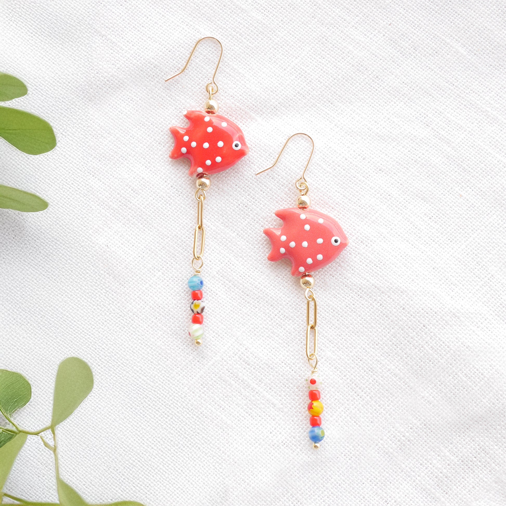 Red fish dangle earrings on a white cloth