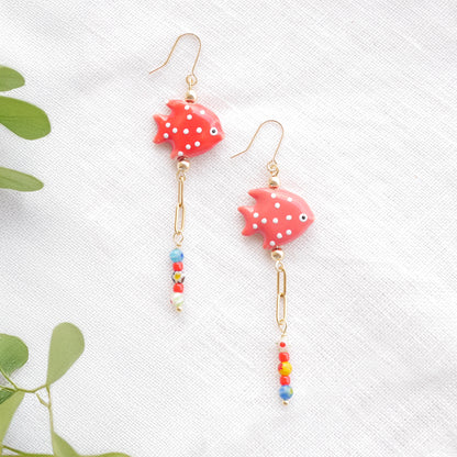 Red fish dangle earrings on a white cloth