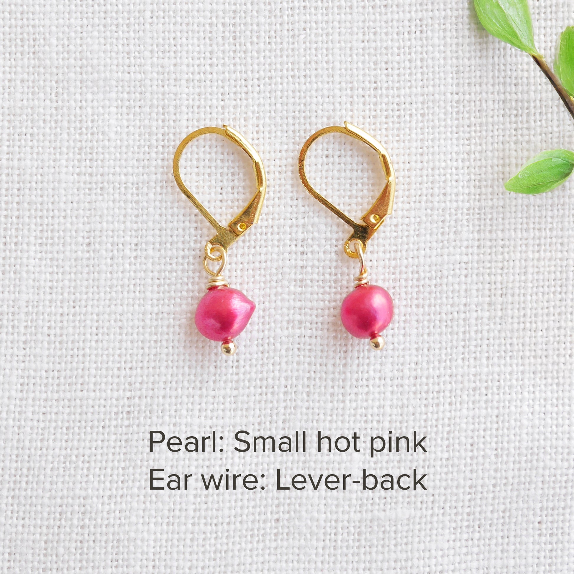 A pair of baroque freshwater pearl earrings on a white cloth.