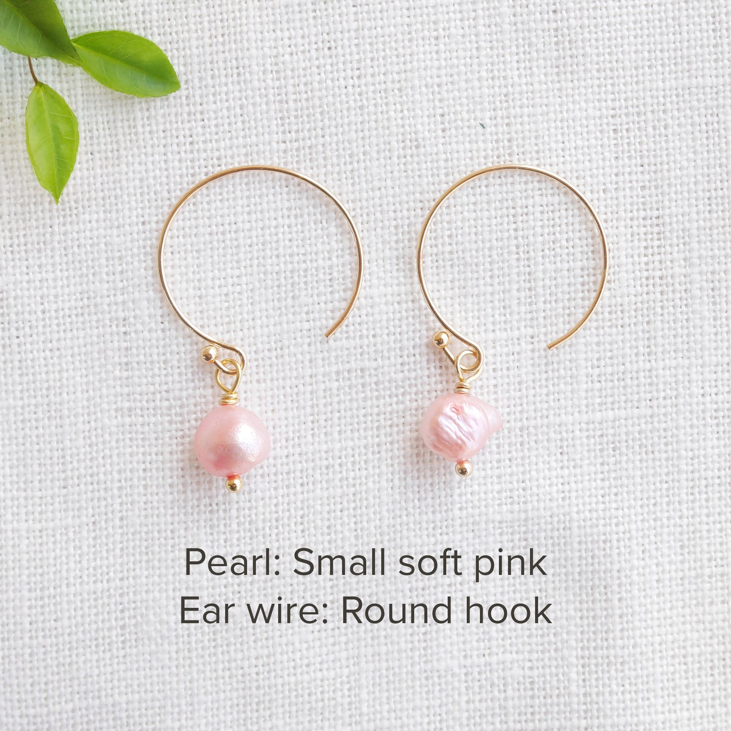 A pair of baroque freshwater pearl earrings on a white cloth.