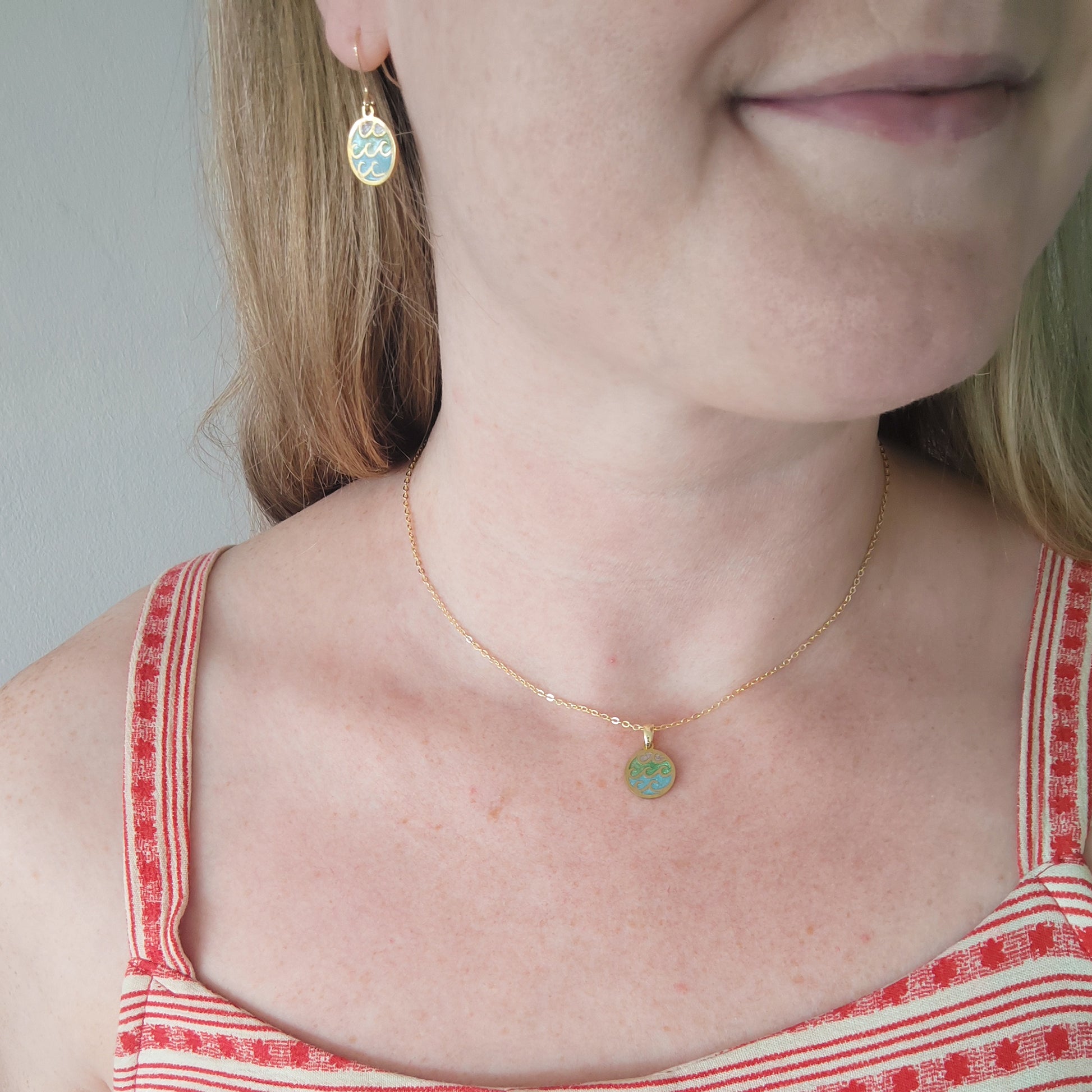 Woman wearing wave gold disc charm necklace and matching earrings.