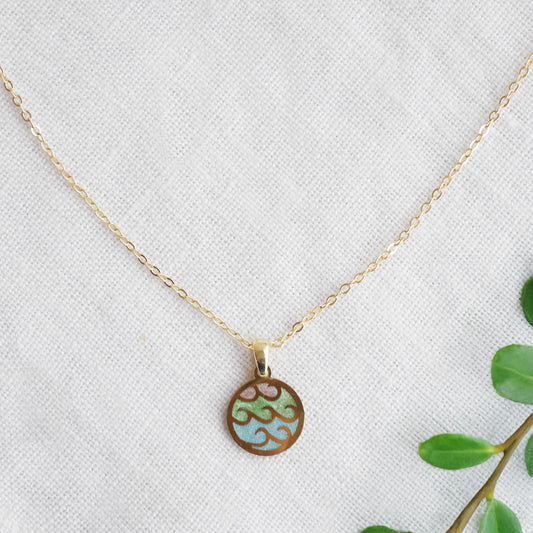 Wave gold disc charm necklace on a white cloth.